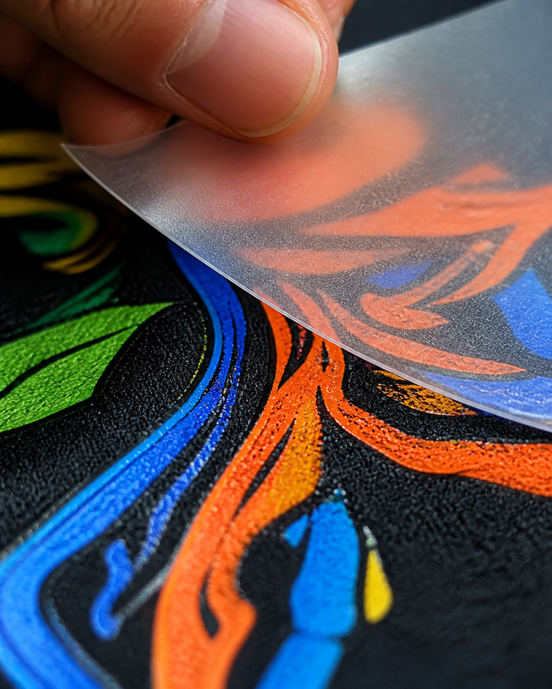Full-color DTF transfer being peeled from a shirt